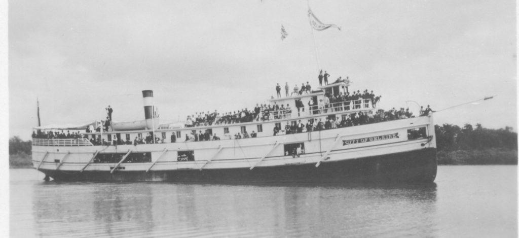 This is a black and white photo of a large boat called the City of Selkirk full of passengers on the river.