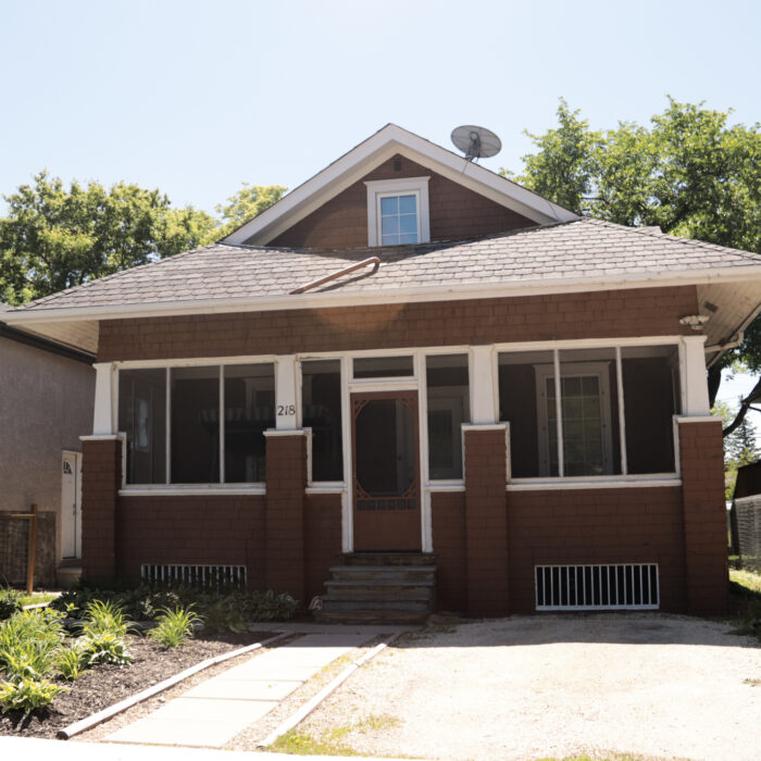 218 McLean Ave, 2020, Selkirk Museum Collection Colour image of a brown house which has symmetrical posts and windows. There is a small window at the peak of the roof