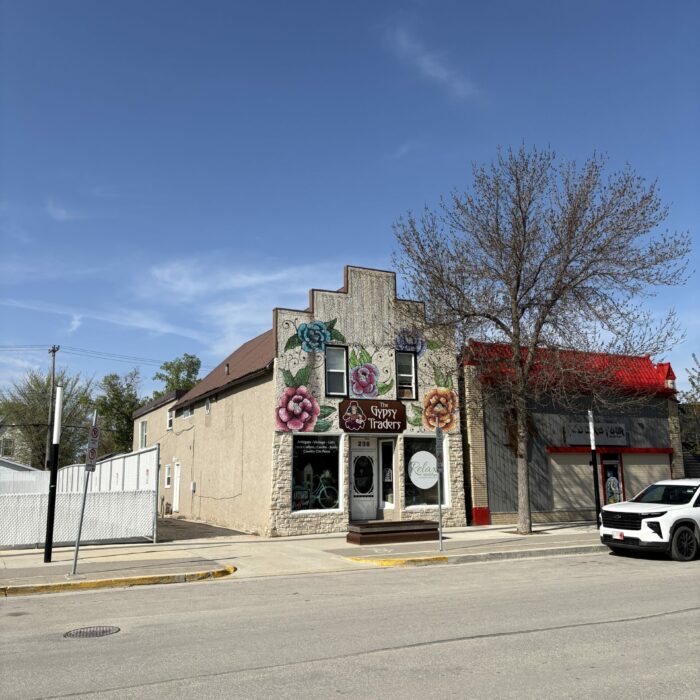 Colour photo of the exterior of a building from across the street. The building is two storeys tall with a boom town style facade. There are large bay windows on the first floor and two vertical windows on the second floor