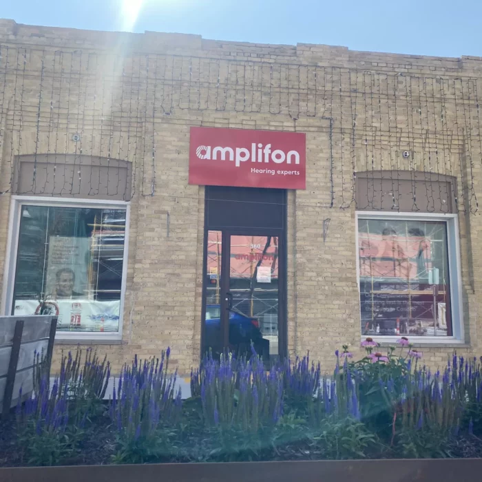 360 Eveline Street, 2024, Selkirk Museum Collection Brick building with purple flowers in wooden planter in front. Sign on the front of the building reads amplifon.