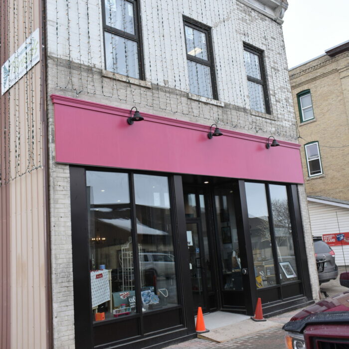 Colour photo of a two story building with a pink banner strip along the middle of the building.