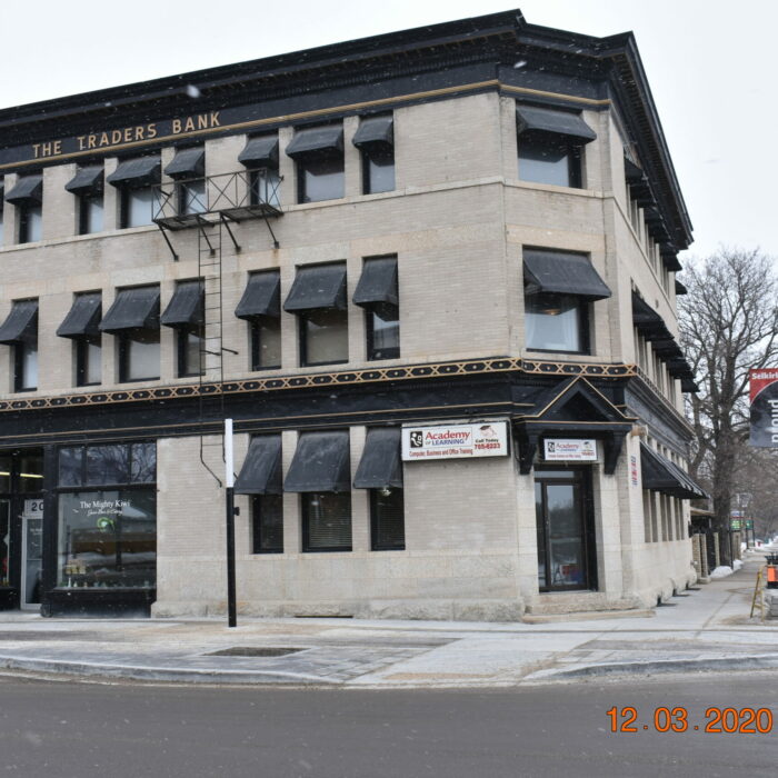 Colour photo of a three-story building with black awnings over the windows. The building has black and gold trim