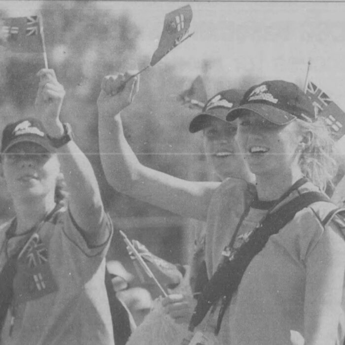 Spectators stand waving flags and smiling