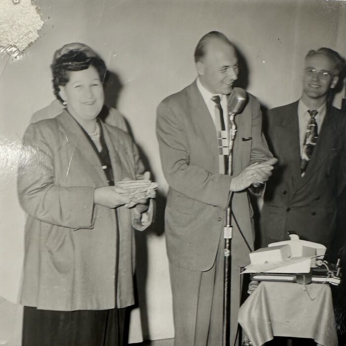 Man standing at a microphone, others smiling and celebrating Foto-Night at Roxy Theatre