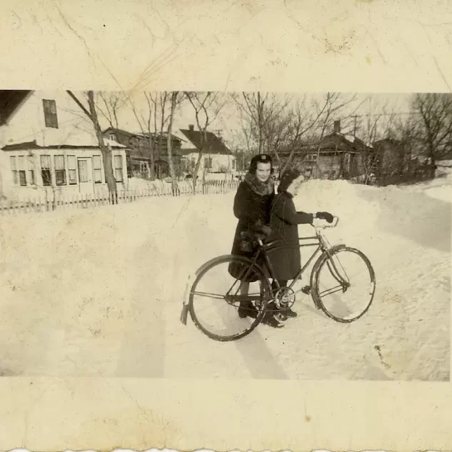 Auntie Jessi in Front of the House on Stanley Ave, Date Unknown, Source Unknown A young woman helping a young girl hold onto a bike