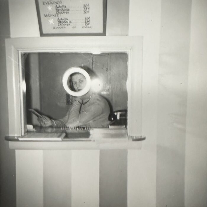 Black and white photo of a woman manning the ticket booth
