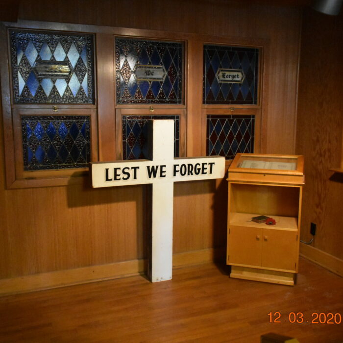 Colour photo of the interior of Memorial Hall Chapel. There is a small white cross at the center of the room and a small podium to the right