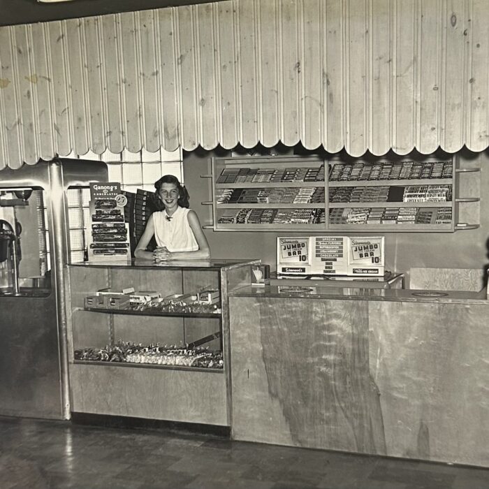A black and white photo of a young girl at a counter. The counter spans the width of the photo