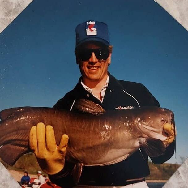 Coloured portrait of Chuck Norquay holding a monster catfish