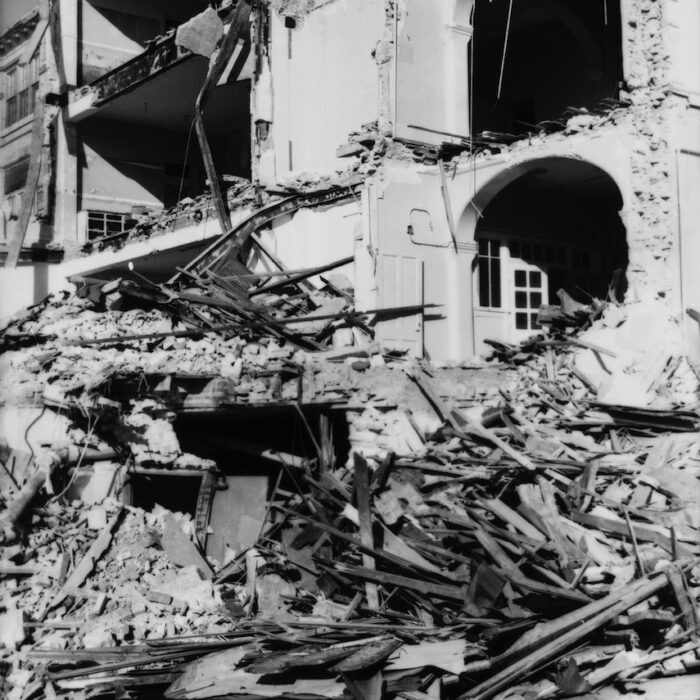 Demolition of Selkirk Mental Hospital 2, Date Unknown, Madness Canada A black and white photo of an excavator demolishing a building. In the background is an archway of another building