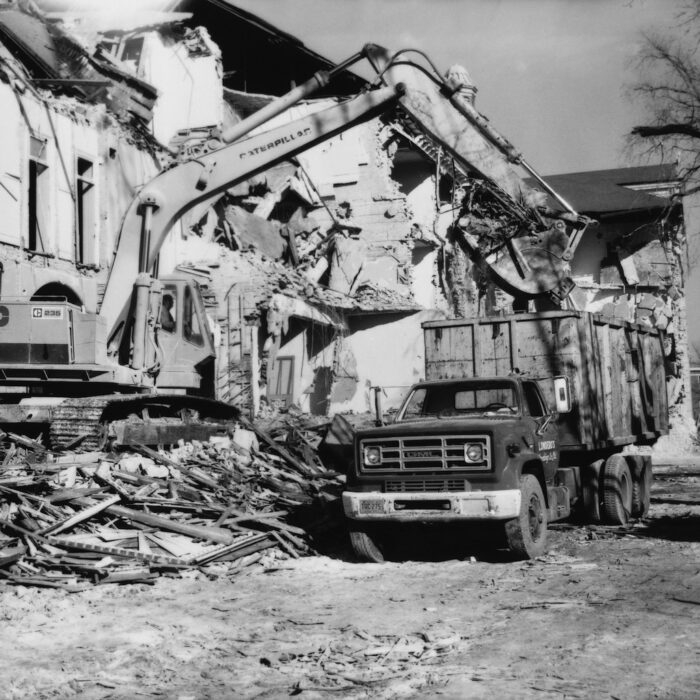 Demolition of Selkirk Mental Hospital 3, Date Unknown, Madness Canada A black and white photo of an excavator loading up a dumb truck with building rubble