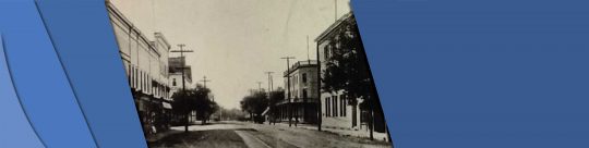 Eveline Headerbar This is a black and white photo of Eveline street with tall buildings on either side from the early 1900s.