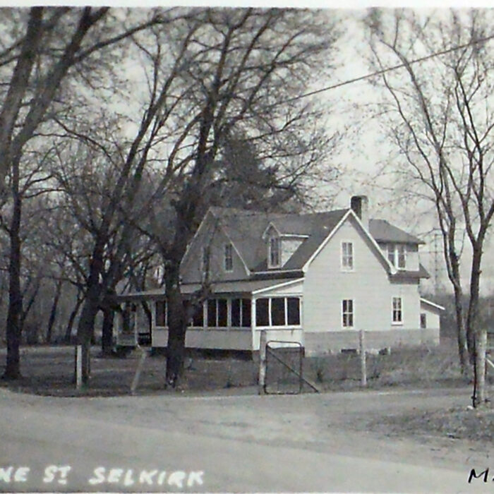 Black and white photo of a street view with a house in the background