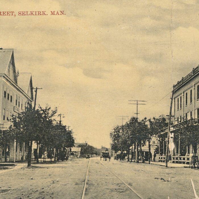 Evelyne Street, 1908, Pat Johnson Sepia-coloured view of Manitoba Ave. There are buildings on either side of the street. There is a telephone pole on the right side of the photo.