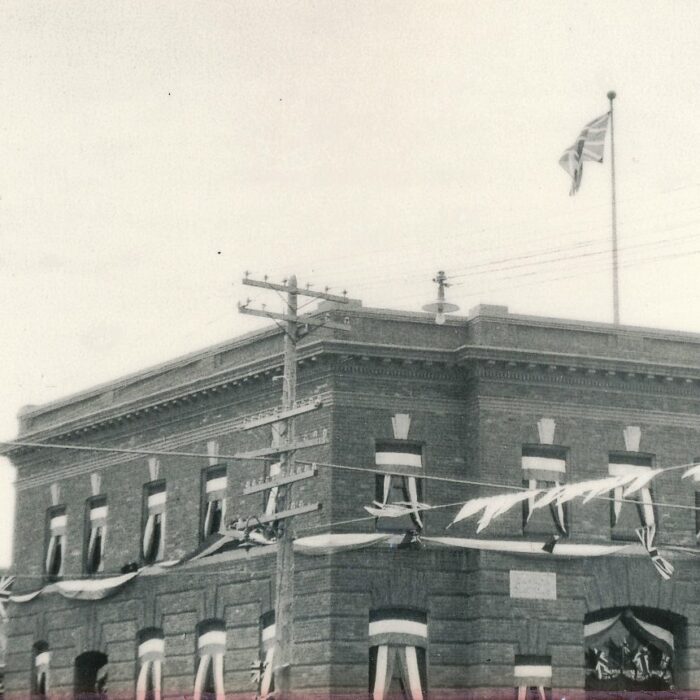 Fair Parade Post Office, 1930, Ted Francis A black and white image of the post office with pennant banners strung across the street in front of the building