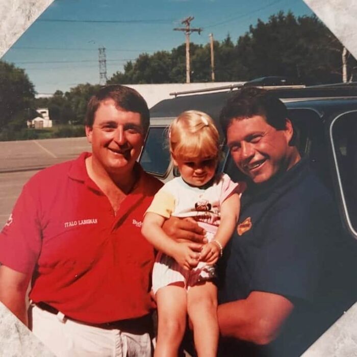 Coloured portrait of Chuck holding his daughter posing for a photo