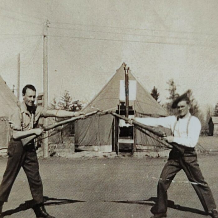John V. Sinclair and Fellow Soldier, c1942-1945, Mae Gulewich Black and white photo of two men holding rifles. In the background is a tent
