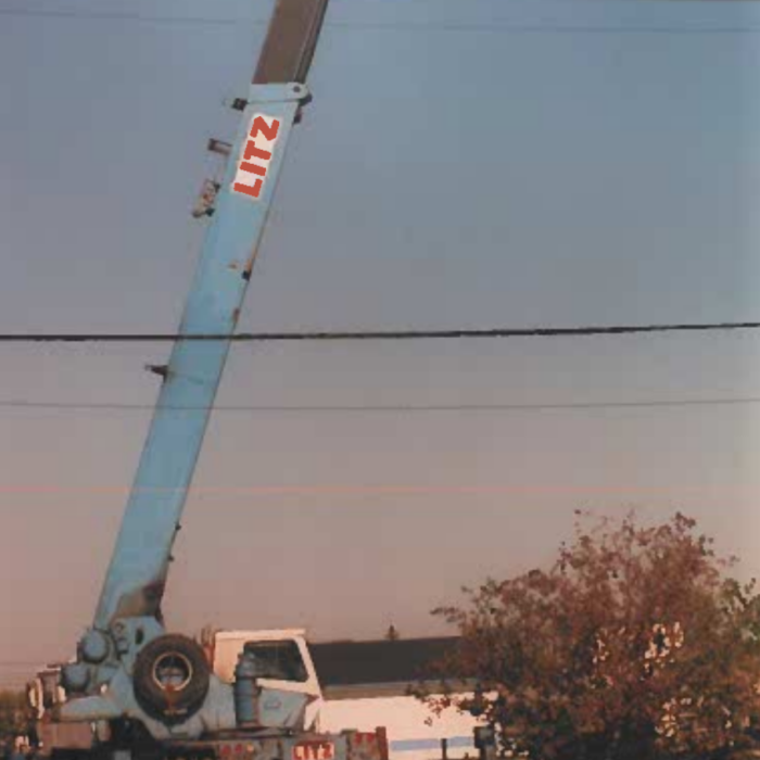 A colour photo of a crane truck with the crane portion extended upwards. The base of the crane is blue. There are red letters on the crane which read 'Litz'