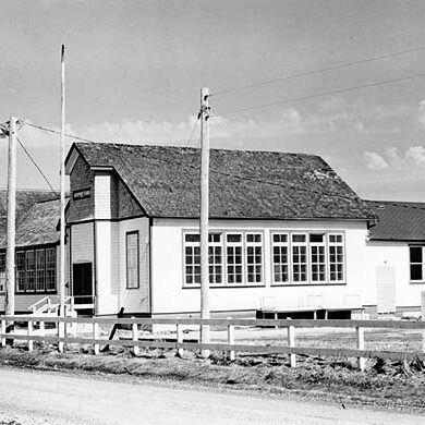 Black and white image of a light coloured building with a dark roof