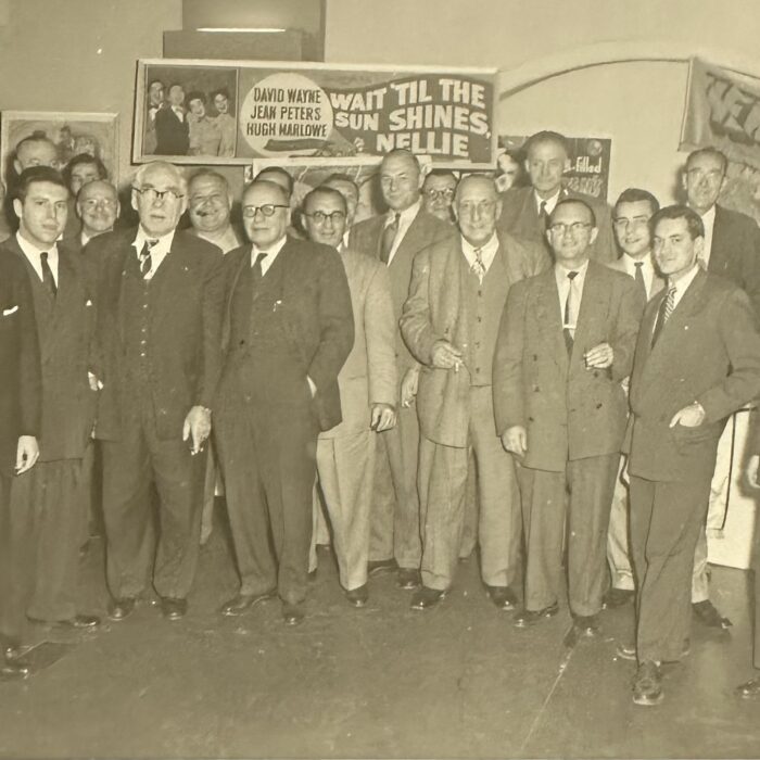 A black and white photo of a group pf men wearing suits and ties