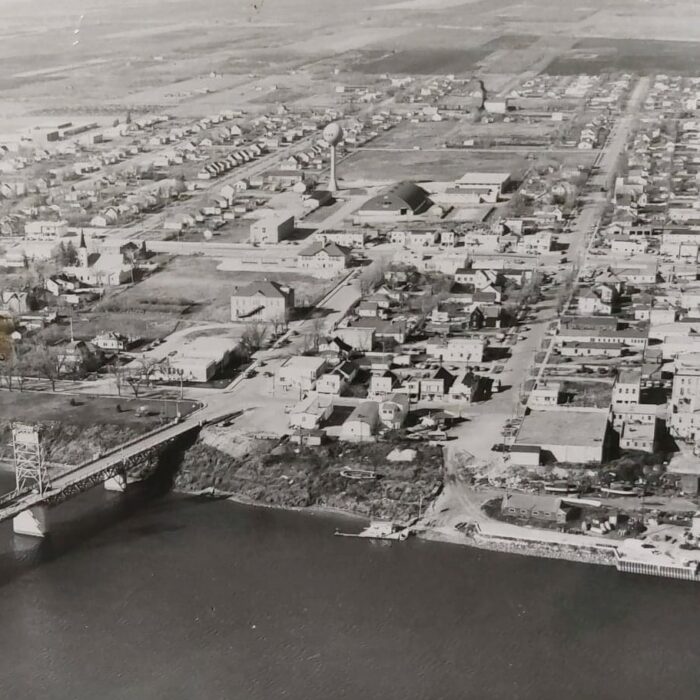Black and white aerial photo of the town of selkirk. On the bottom portion of the photo is the river. on the left side of the photo is the Selkirk Lift Bridge