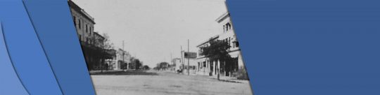 Manitoba Headerbar This is a black and white photo of a street with tall building on either side.
