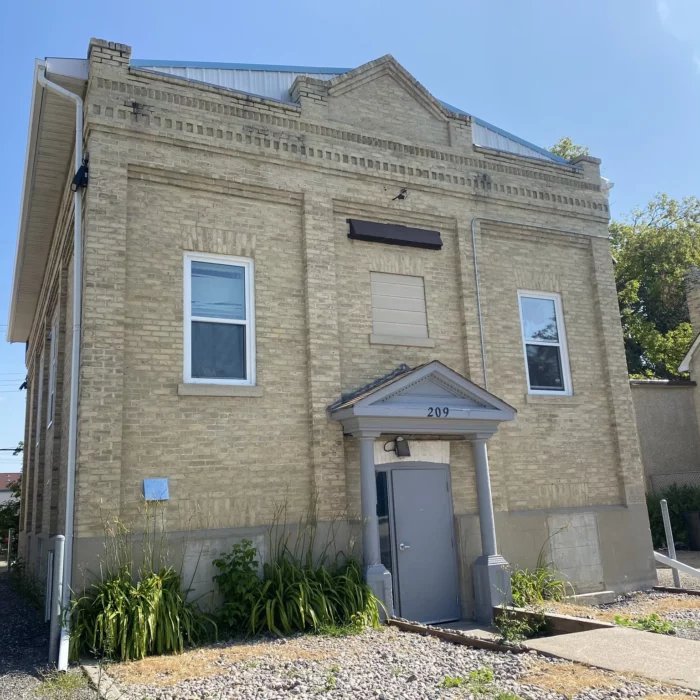 Brick Building with two windows and an archway over the door.