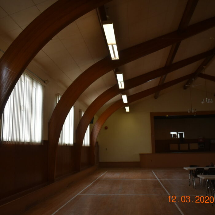 A colour image of the interior of a hall. There are wooden beams on the ceiling