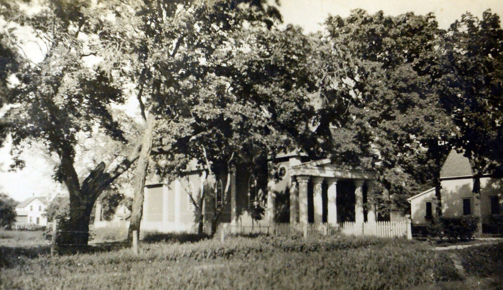Black and white photo of a church secluded by trees