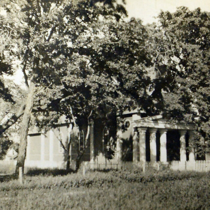 Black and white photo of a church secluded by trees