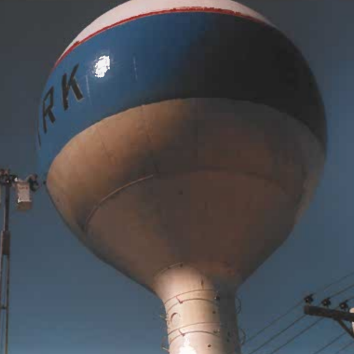 Colour photo of the side of the water tower. The painters in the crane on on the left side