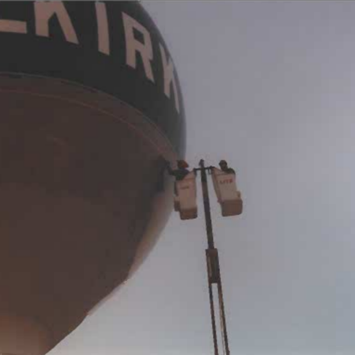 Colour image of painters in a crane lifted in the air to paint the top of the water tower
