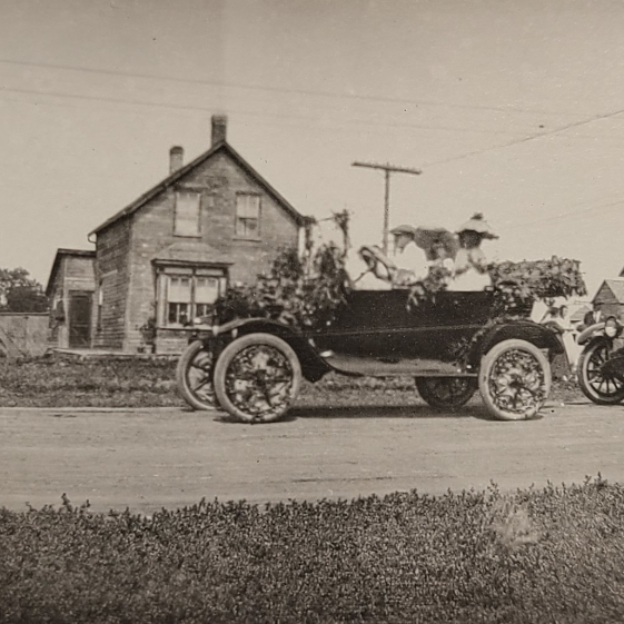 Black and white photo of old cars driving down the street