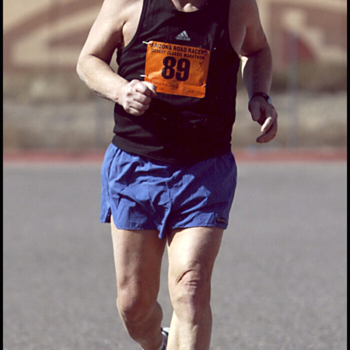 Podruchny at Phoenix, 2004, Thomas Podruchny Man is positioned centrally in the frame running towards the camera. He is wearing a black shirt and blue shorts. The number 89 is pinned to his shirt. He is smiling