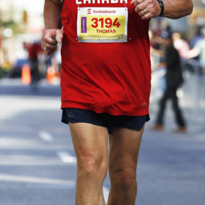 Podruchny at Toronto, 2017, Thomas Podruchny Tom positioned centrally in the frame, running towards the camera. He is wearing a red shirt and black shorts the number 3194 is pinned to his shirt