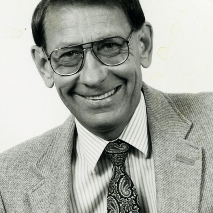 Podruchny at the Comp, 1973, Thomas Podruchny Black and white portrait headshot of man wearing a button up shirt, tie, and suit jacket