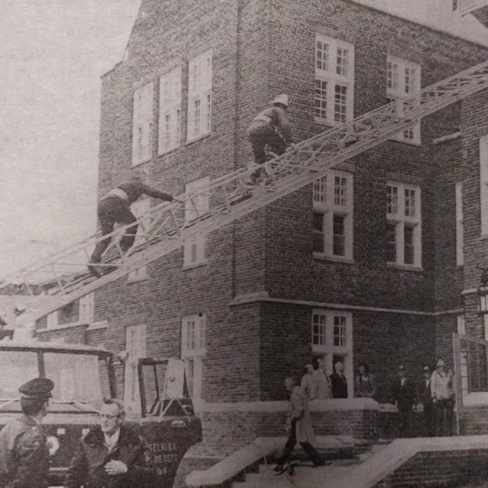Fire Drill Organized by Ted Wozny at the Selkirk Mental Health Centre, 1978, Selkirk Enterprise Centennial Edition Image showing a fire truck with the ladder extended. Two firemen are climbing the ladder to perform a fire drill at Selkirk Mental Health Centre
