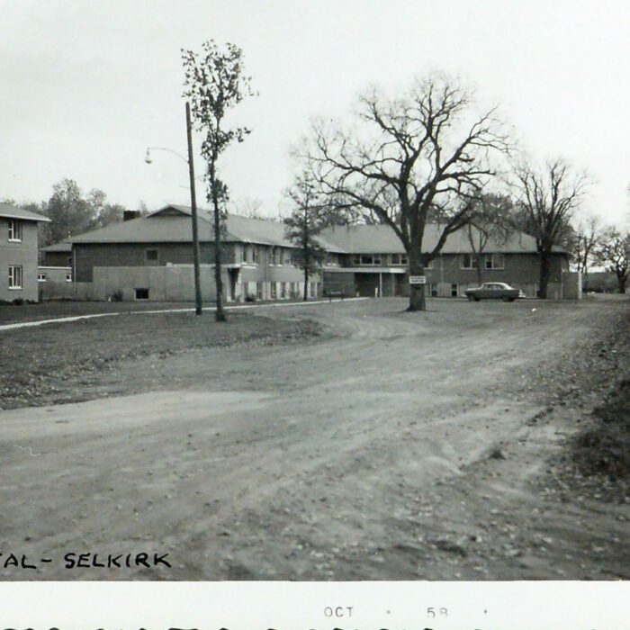 Selkirk General Hospital, 1958, Archives of Manitoba, George Harris Fonds, Black and white photo with structures in the distance and trees