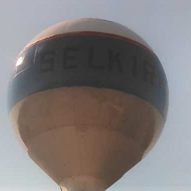 Colour photo of the bowl of the water tower. It is mostly white with a blue band trimmed with red. The letters are black and read 'selkirk'