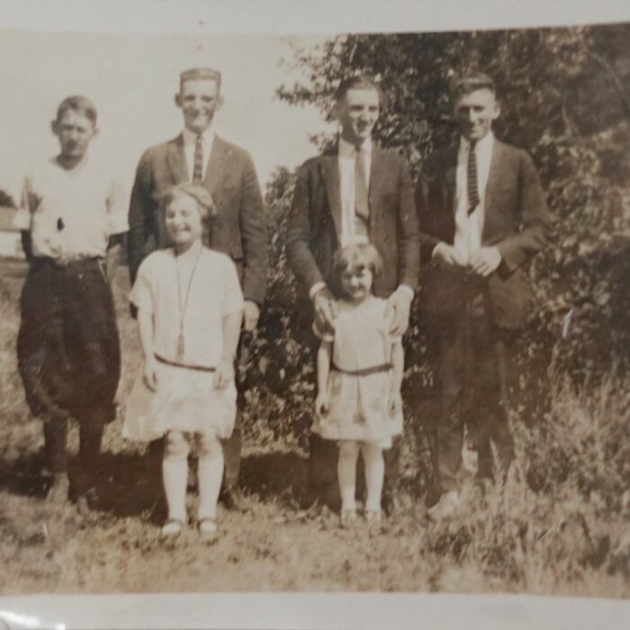 Stuart Family, Date Unknown, Source Unknown A sepia-coloured photo of a family standing outside beside a bush