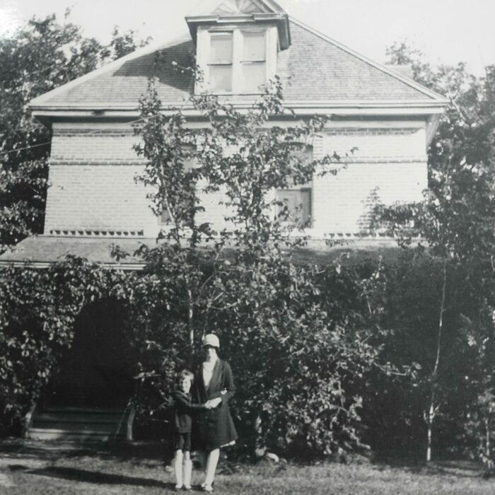 Stuart House, Date Unknown, Source Unknown A black and white photo of a large two-story house. There is a person standing at the front of the house. There are lots of trees growing around the house
