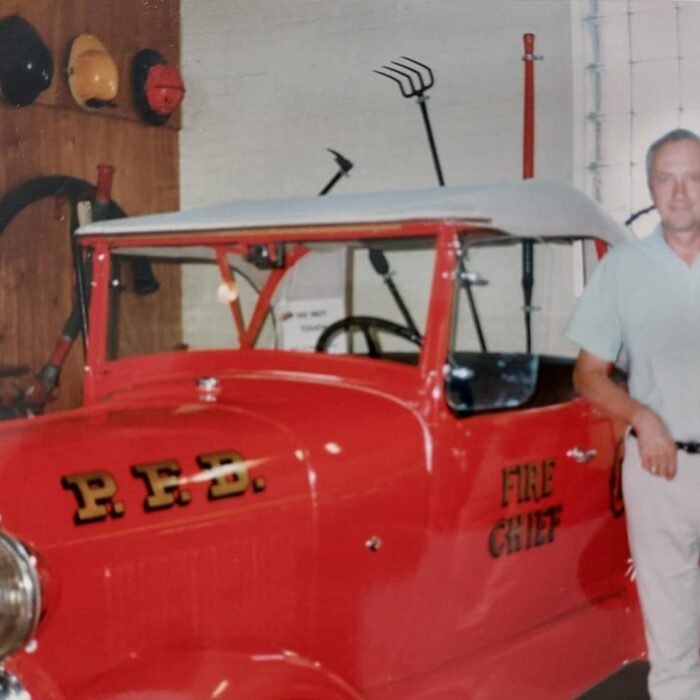 Ted Wozny with Fire Chief Car, 1991, Ted Wozny Coloured portrait of Ted Wozny posing in front of a red fire chief car