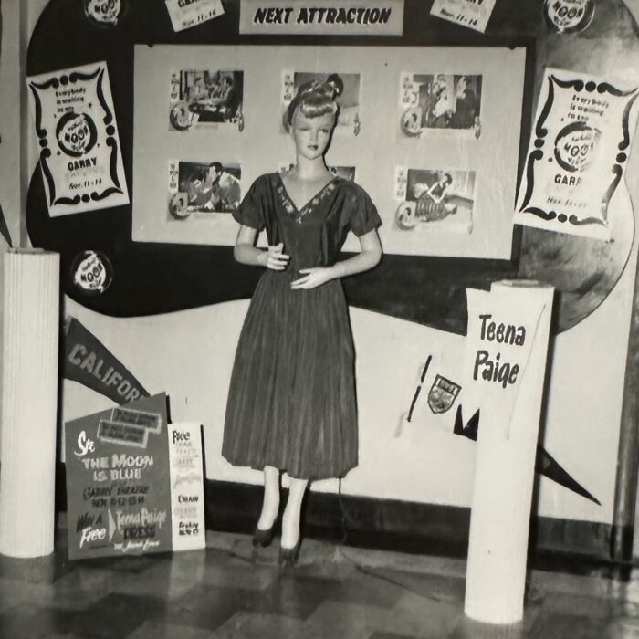 A black and white photo of a women standing in front of a decorated backdrop