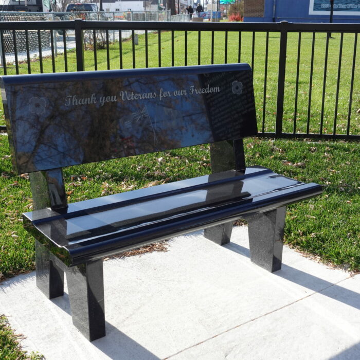 A colour photo of a black stone bench engraved with the words, "Thank you veterans for our freedom"