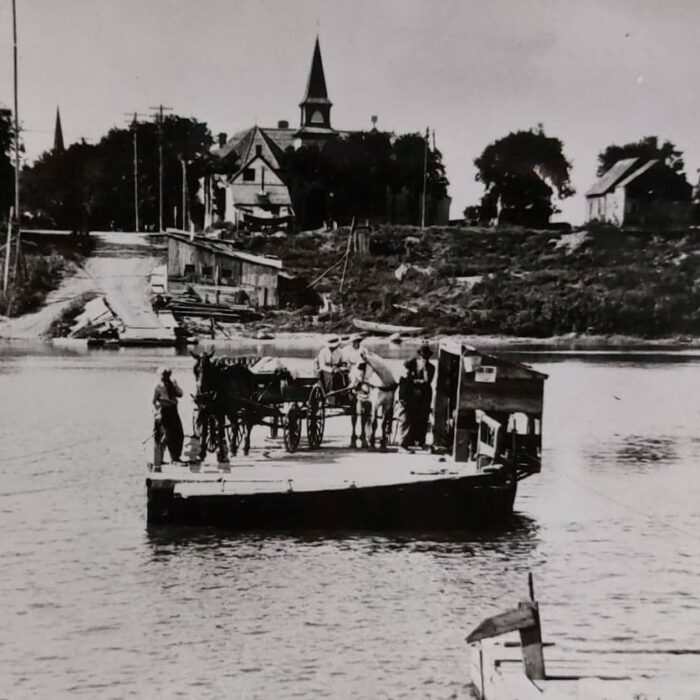 Selkirk Ferry full of people sailing mid river. View of Knox Presbyterian Church in the background