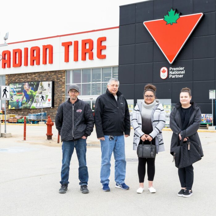 A colour photo of a group of people standing in front of Canadian Tire