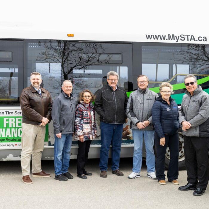 Colour photo of a group of people standing in front of a bus