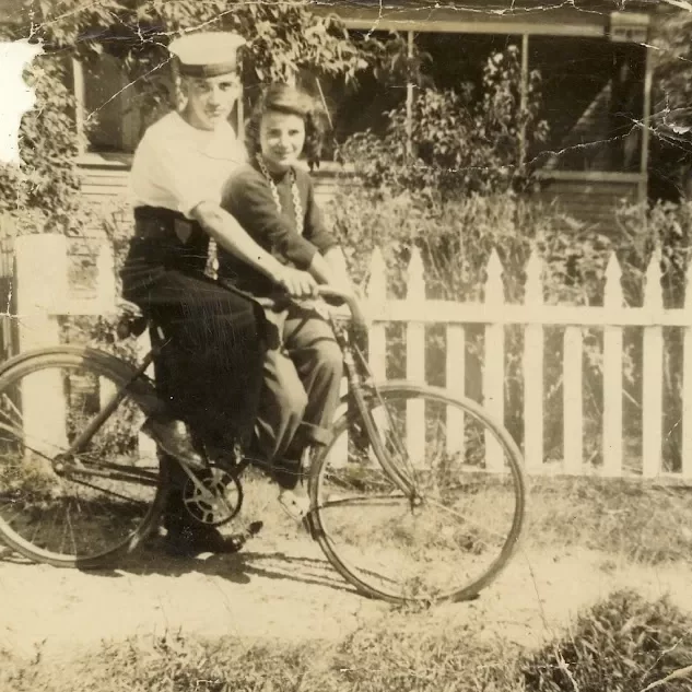 Uncle Art and aunt Dorothy in front of Their Home on Stanley Ave. All the Langlois Boys Sent Half Their Army Pay Home. Peter and Jessi Moved Back to Selkirk and Bought this Home in 1942, Date Unknown,Jock Langlois A young couple on a bike in front of a home in black and white