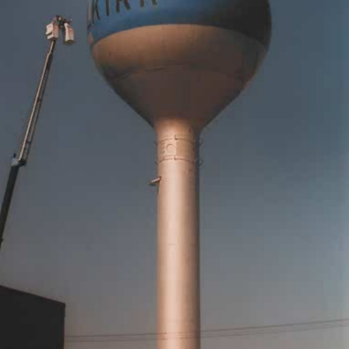 A colour photo of the Selkirk Water Tower being painted by painters in a lift crane
