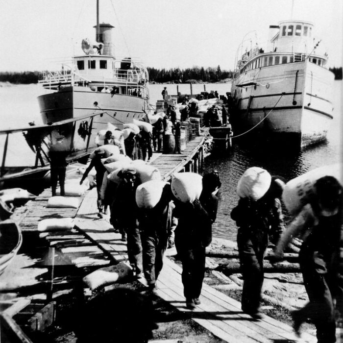 Wolverine and Bradbury, 1950's-1960's, Boyd Hall Black and white picture of men hauling sacks over their shoulders from the ships Wolverine and Bradbury